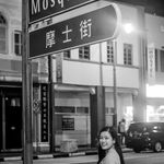 Black and white photo of a woman smiling on an urban street at night.